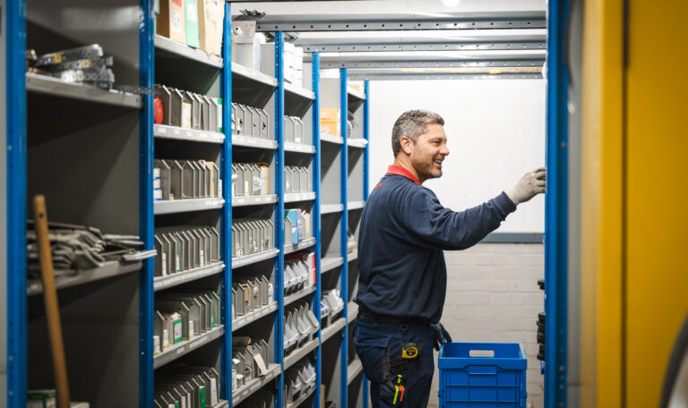 Medewerker pakt iets uit het magazijn en lacht